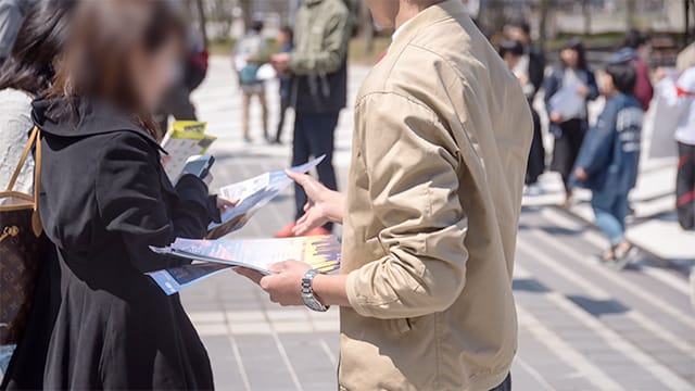新入生に向けて裏に広告の入った勧誘チラシを渡している写真